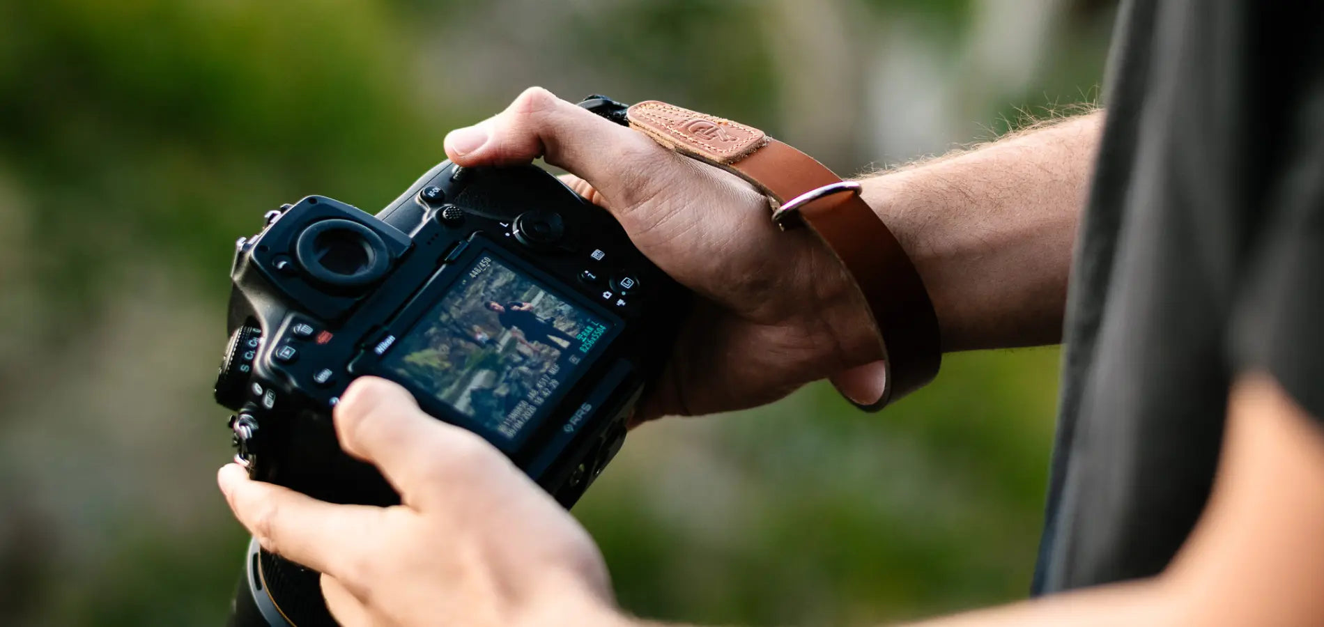Photographer holding camera with leather wrist strap