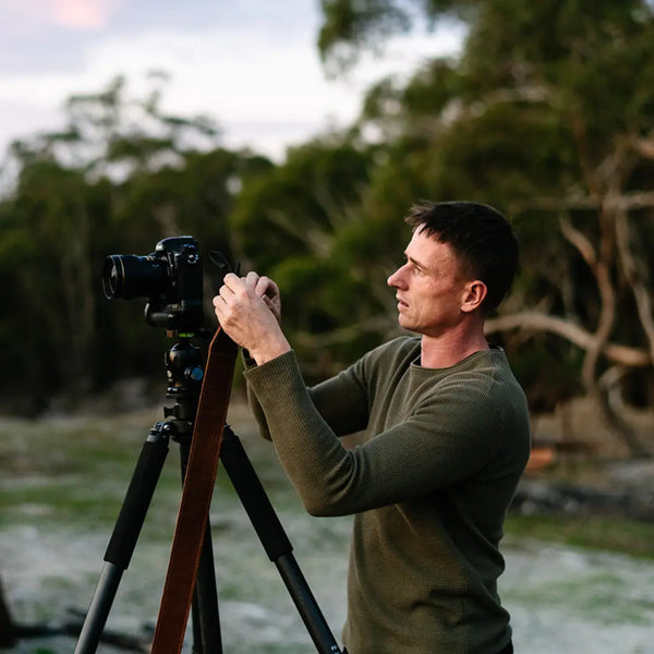 landscape photographer using tripod after removing leather camera strap