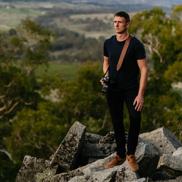 Male Photographer on mountain using leather camera straps